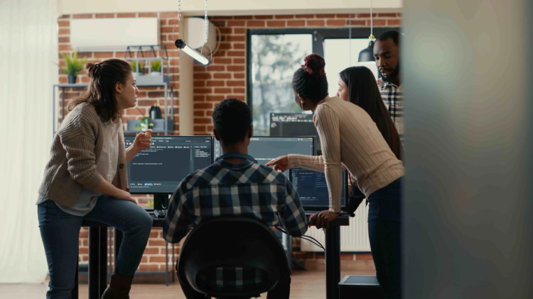 In-House Developer vs WordPress Agency: Which Should You Hire? 4 Group of WordPress developers discussing project management and collaborating in a modern office