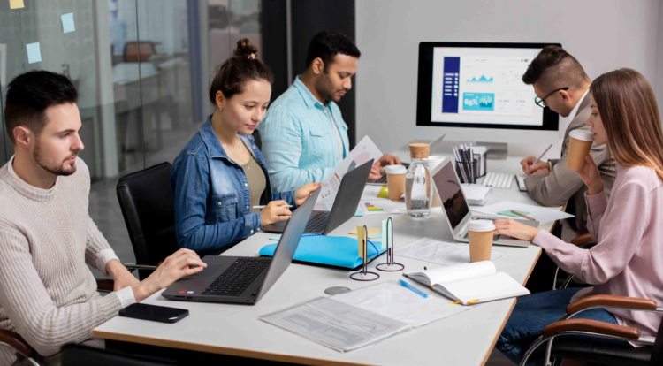 In-House Developer vs WordPress Agency: Which Should You Hire? 3 Team working in a modern computer lab, collaborating on a WordPress project with laptops and coding software